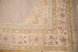 Corner detail of an antique Agra carpet's floral border in pale lavender, mauve, and dusty gold tones.