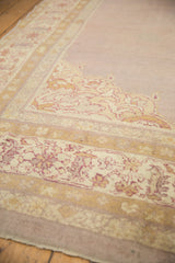 Dusty gold and ivory plant motifs on the time-softened mauve corner of an antique Agra carpet.