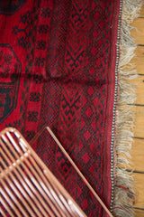 Vintage Ersari carpet with cherry red, navy teal geometric patterns, original fringe, and selvage.