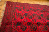Cherry red Ersari rug with full pile, dark teal elephant footprint guls, and fringed edge.