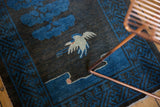 Close-up of vintage Peking runner, showing pictorial pale bird and blue tree on charcoal ground.