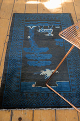 Fringed end of the vintage Peking runner, with blue geometric border on charcoal.