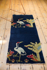 A vintage Chinese pillar rug with pictorial birds and botanicals against a deep cobalt blue field.