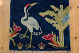 Artful rendering of a bird and landscape on the dense, cobalt blue pile of a vintage Peking rug.