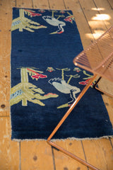 Lifestyle view of a vintage Peking pillar rug with bird motifs against a saturated cobalt blue background.