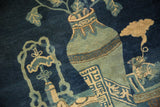 Detail of an antique Peking rug with celadon vase, geometric patterns, and indigo.