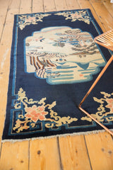 Angled view of a collector's antique Peking rug with its pictorial medallion and indigo field.