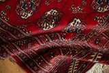 Intricate Tekke-inspired geometric border and cherry red pile of vintage Bokhara rug.