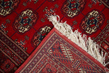 Vintage Bokhara rug detail: rich cherry red pile, hand-knotted foundation, and white fringe.