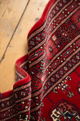 Super fine vintage Bokhara rug's rolled edge, with cherry red wool, high sheen, and navy geometric details.