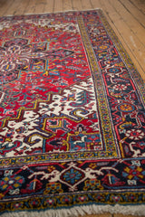 Vintage Heriz carpet's geometric floral design in cherry red, ivory, navy blue, and fringe.