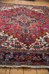 Vintage Heriz carpet's full pile displays geometric floral motifs in cherry red, navy, ivory.