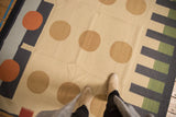 Contemporary kilim rug with ivory field, camel circles, charcoal, emerald green borders.
