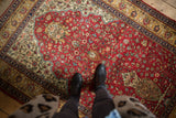 Intricate tree of life and millefleur design on the plush, cherry red pile of a vintage Romanian rug.
