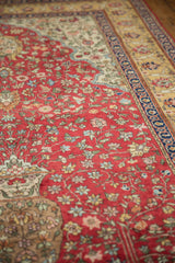 Close angled view of a vintage Hereke design rug's plush pile and red floral millefleur pattern.