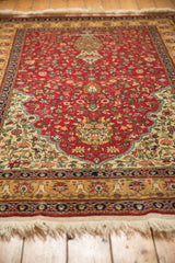 Angled view of a vintage Romanian rug showing its full pile, cherry red field, and detailed borders.