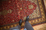 A standing perspective over the vintage rug's dense millefleur pattern on a cherry red field.