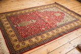 Full perspective of a vintage Romanian rug with a red unidirectional pattern and floral border.