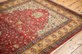 Intricate blossomed floral arabesques on the sand and ivory borders of a vintage cherry red rug.