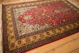 Angled view of a vintage Romanian Hereke rug with its cherry red tree of life pattern.
