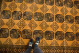 Saffron yellow field with dark navy elephant footprint guls and diamond shadow medallions.