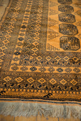 Corner of a vintage Daulatabad carpet with a saffron field, navy geometric borders, and open fringe.