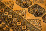 Plush saffron yellow wool pile with dark navy elephant footprint gul motifs and border detail.