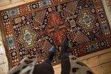 Overhead view of the vintage Romanian rug's large scale birds and geometric medallions in navy and rust.