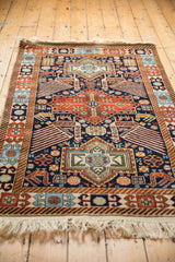 Angled view of a vintage Romanian Akstafa rug's geometric birds and triple medallion design.