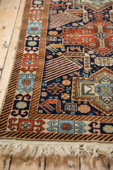 Corner view of a vintage Romanian rug showing its geometric border, intact side cord, and ivory fringe.