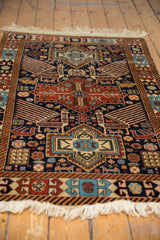 Angled view of a vintage Romanian Akstafa rug with geometric bird and medallion motifs.