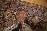 Overhead view of the vintage Romanian rug's central rust medallion and surrounding geometric bird motifs.