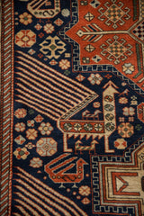 Geometric bird motifs with finned feathers on the navy blue field of a vintage Romanian rug.