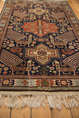 Corner view of a vintage Romanian rug showing the detailed geometric border and secured ivory fringe.