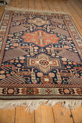 Low angle view of the vintage Romanian rug's plush pile, navy field, and geometric bird motifs.