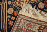 Corner detail of a vintage Romanian rug showing its dense navy pile, fringe, and hand-knotted back.