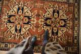 Looking down at the bold starburst medallions of a vintage Romanian Kazak design rug.