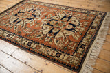 Vintage Romanian Kazak rug's plush pile and geometric starburst design seen from an angle.