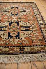 Low angle of a vintage Romanian Kazak rug's plush rust pile, navy medallions, and ivory fringe.