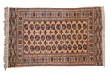 Vintage Pakistani Bokhara rug with columns of elephant foot motifs in red and charcoal on a golden field.