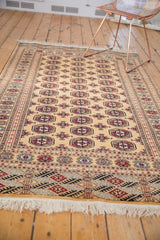 Vintage Pakistani Bokhara rug seen from an angle, showing its triple column of repeating medallions.
