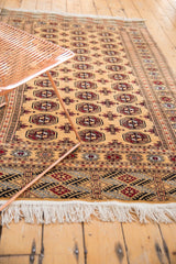 Angled view of a vintage Pakistani Bokhara rug showcasing its golden field and traditional design.