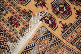 Folded corner of a vintage Bokhara rug reveals the tight hand-knotted weave and plush golden pile.