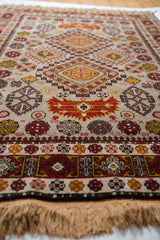 A low-angle view showing the plush, even pile of a vintage Romanian Shirvan rug with rust and gold geometric motifs.