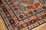 Intricate geometric border and floral motifs in rust and gold on the rug's plush, full pile.