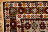 Close-up of a vintage Romanian rug corner, showing geometric floral borders and its original fringe.