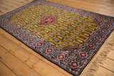 Vintage Romanian Shirvan rug from an angle, highlighting the dense boteh pattern on a rich gold ground.