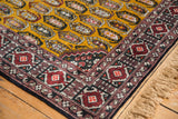 Corner of a vintage Romanian rug showing its plush gold pile and intricate geometric border design.