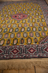Angled view of a vintage Romanian rug's plush gold pile and repeating boteh design.