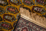 Corner view showing the hand-knotted back, original fringe, and dense gold wool pile.